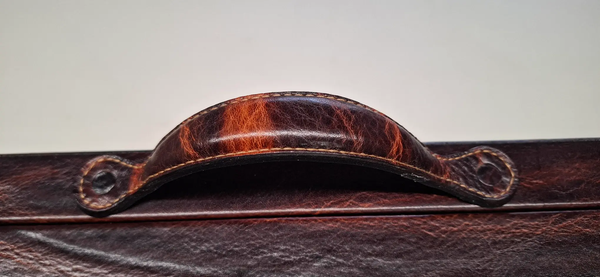 Close-up of a handcrafted leather handle on a luxury backgammon board, showing fine stitching and aged leather.